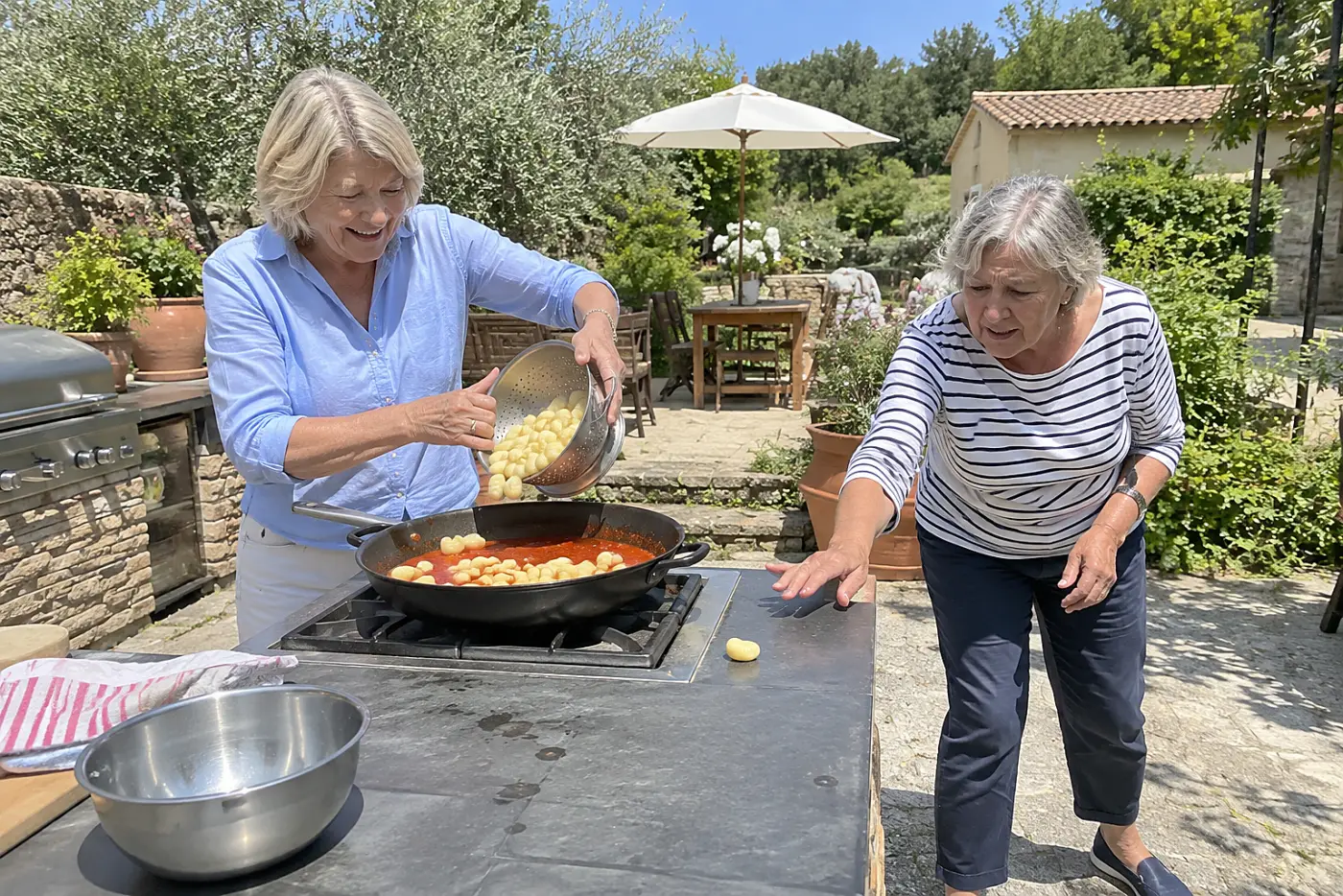 A woman adds gnocchi to tomato sauce at an outdoor cooking station.